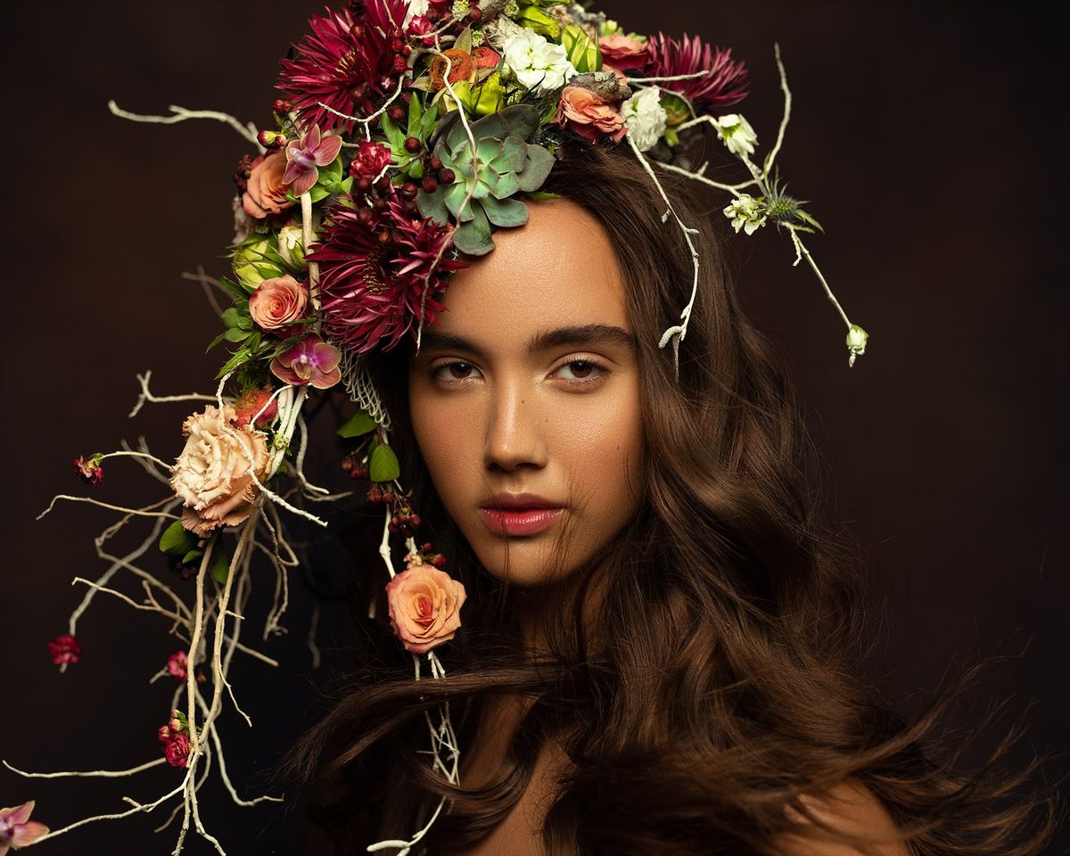 A portrait under a cascading crown of roses and trailing vines.