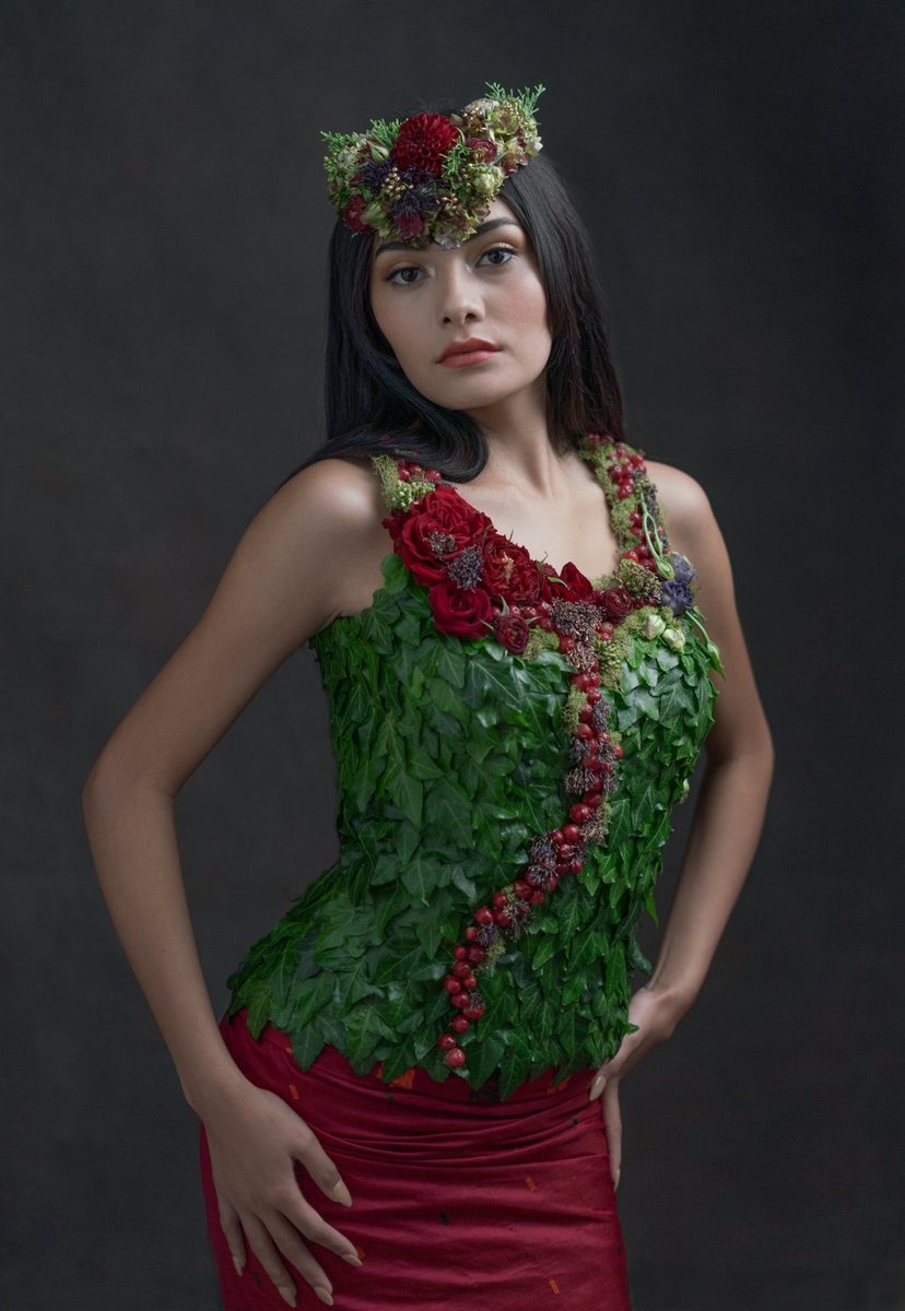 A bodice of green leaves over a deep red skirt, with a flower crown.
